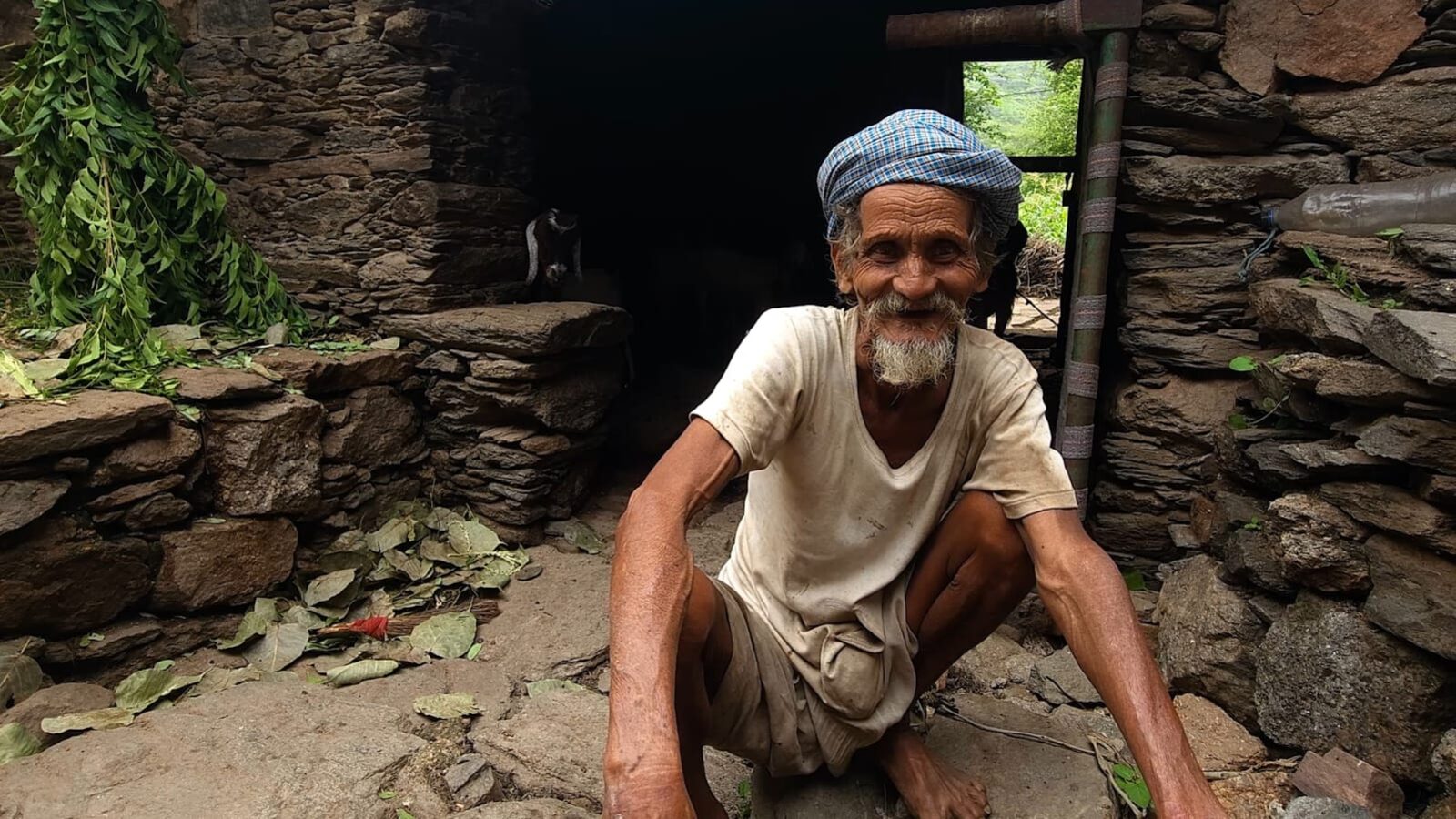 A 72-year-old Aravali shepherd smiling outside his stone hut