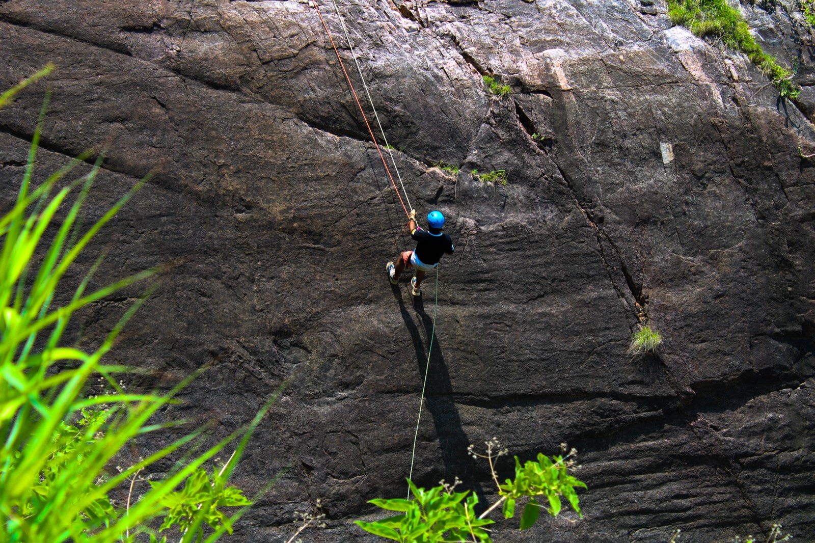A rappeller descending a granite cliff in the Aravali hills